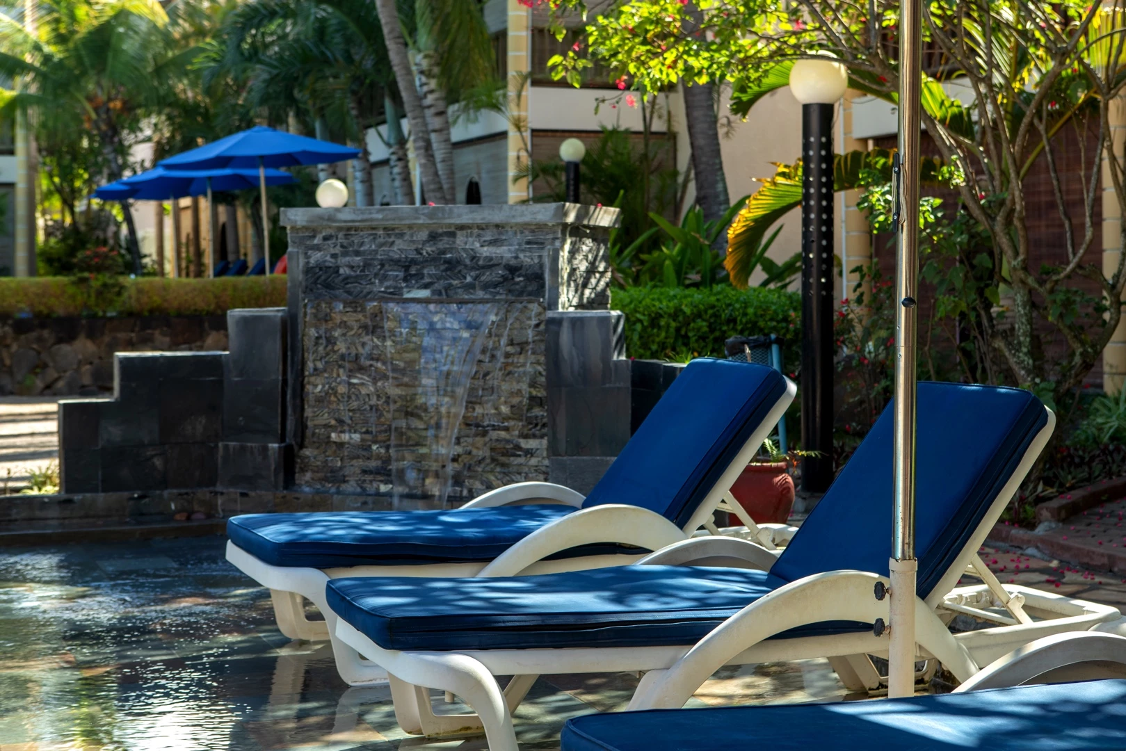 Sun loungers by the pool at Le Palmiste Resort & Spa surrounded by tropical greenery